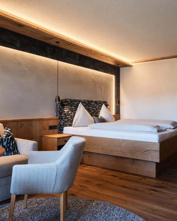 Modernes Hotelzimmer mit Holzmöbeln, Doppelbett und gemütlicher Sitzecke